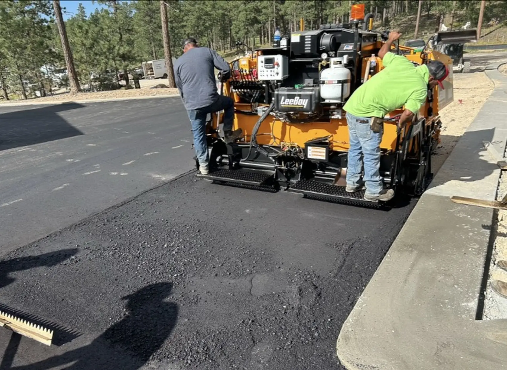 Asphalt paver laying a commercial surface against a new concrete curb